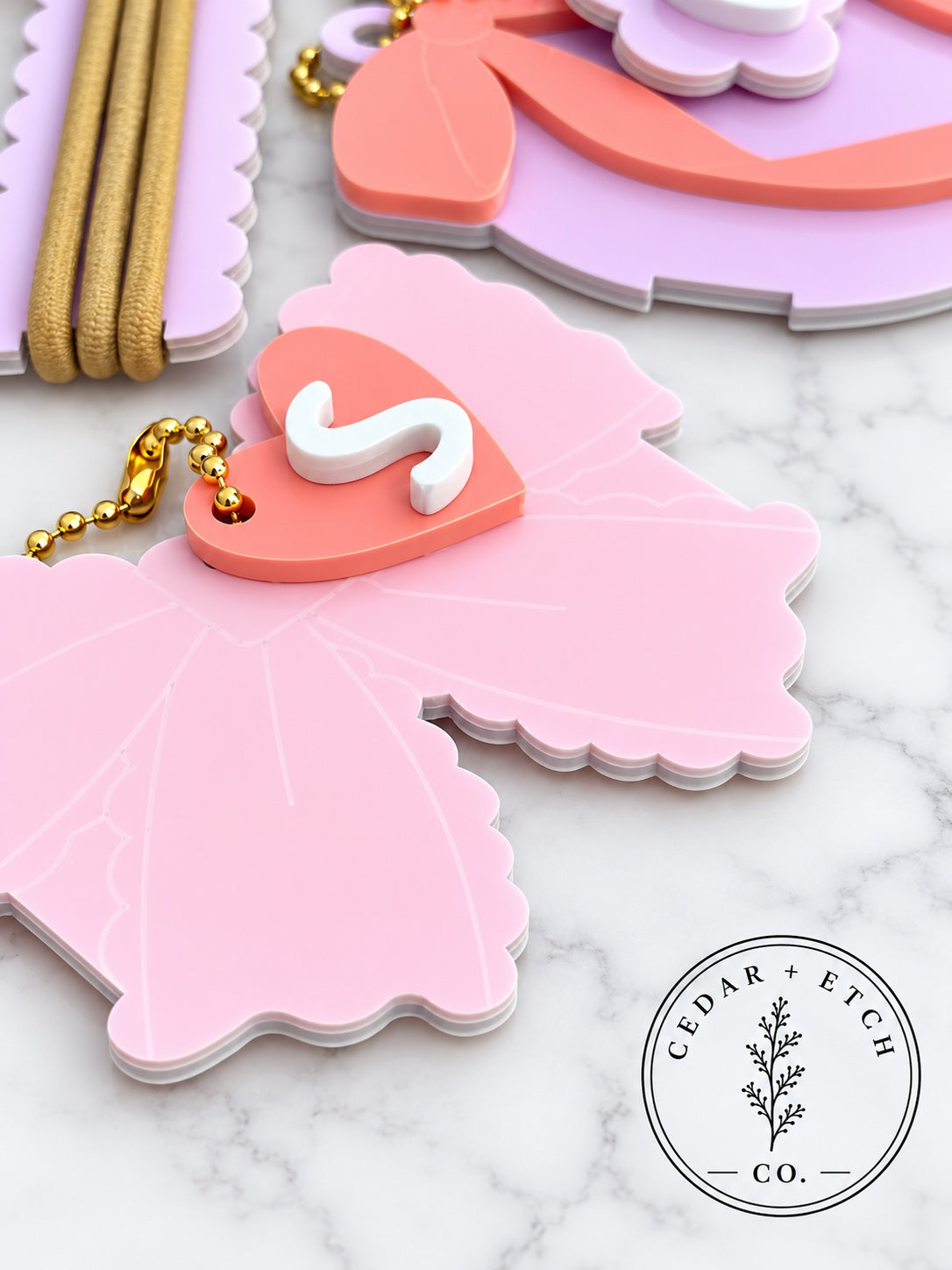 Close-up of glossy acrylic coquette hair tie holder keychain and personalized initial tag